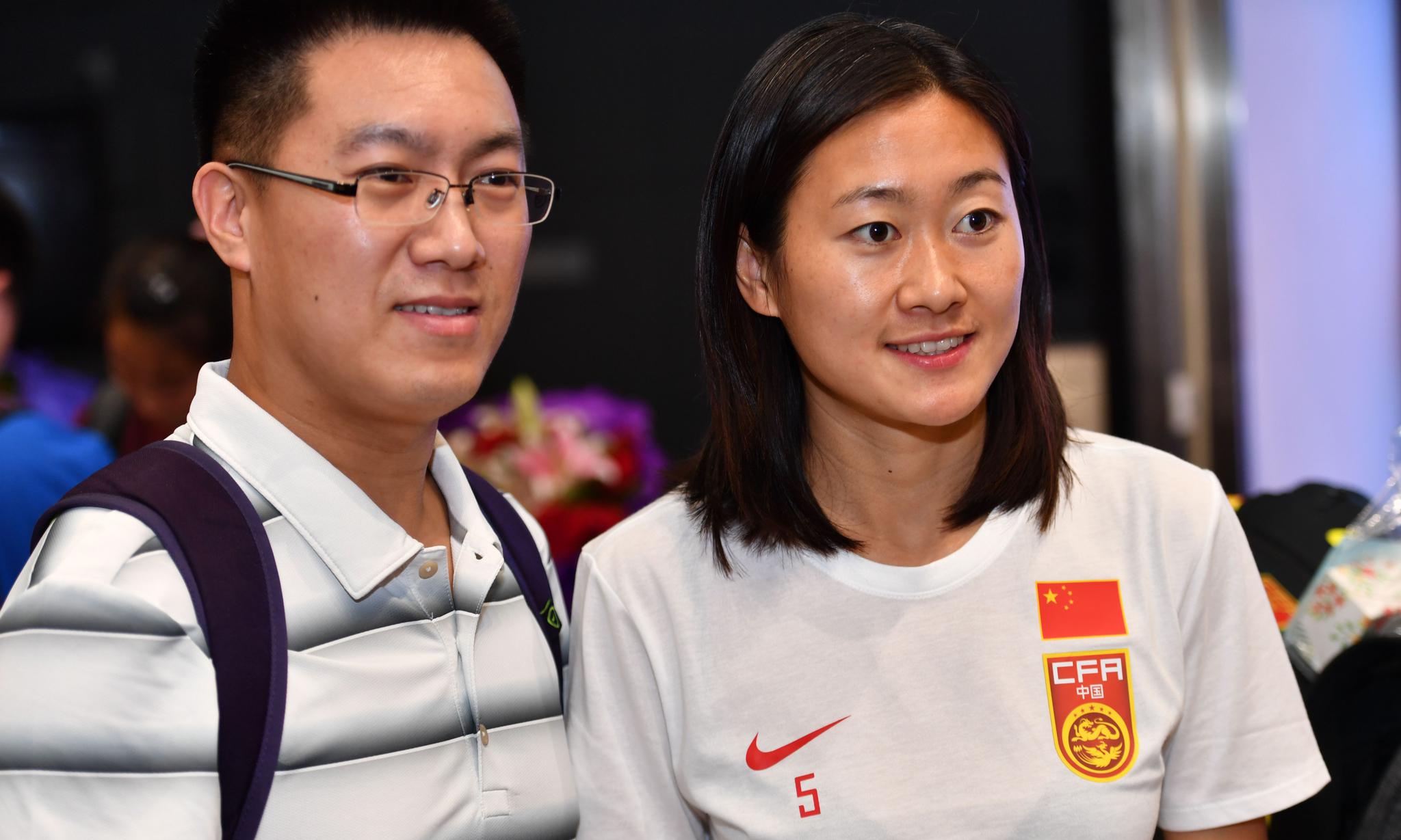 6月27日,中国女足球员吴海燕(右)在北京首都国际机场与球迷合影